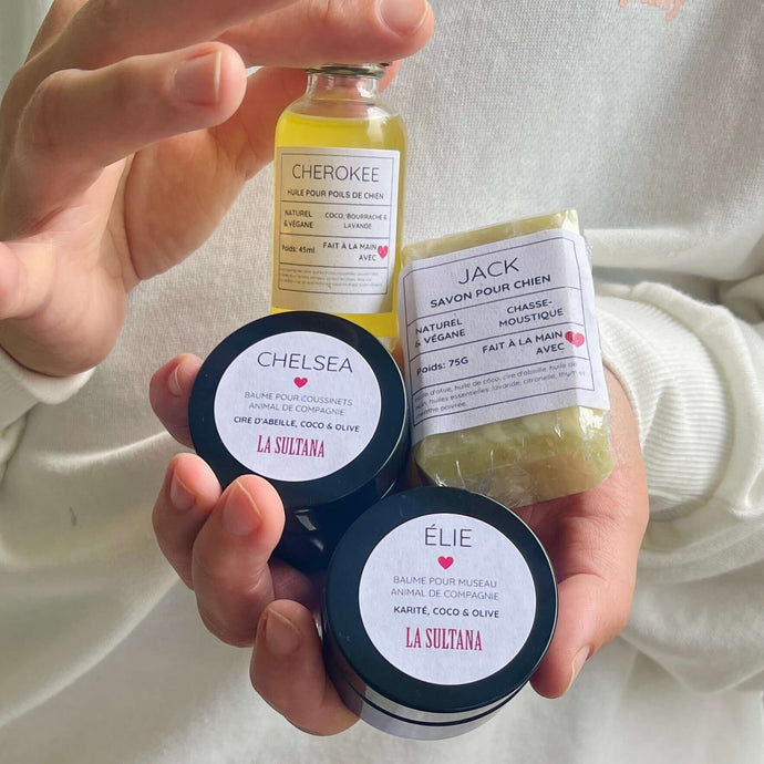 Une personne tient dans ses mains un Ensemble MON MEILLEUR AMI, qui comprend une bouteille d'huile « CHEROKEE », un pain de savon « JACK », un pot de baume pour les pattes « CHELSEA » et un pot de baume pour le museau « ÉLIE ». Ces produits pour animaux de La Sultana Savonnerie | Savons et soins naturels faits main | Le Québec est labellisé 100% naturel, végétalien et fait à la main.
