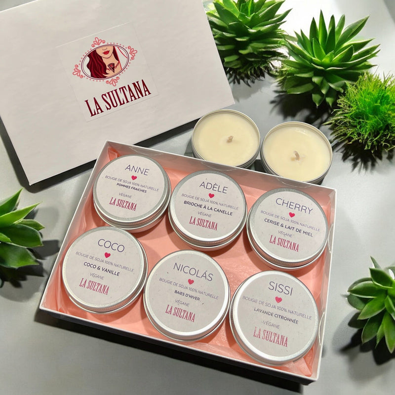 Chargez l&#39;image dans la visionneuse de la galerie, Un coffret de six bougies parfumées Ensemble LUZ de La Sultana Savonnerie, fabriquées comme des bougies de soja, est présenté dans une boîte blanche arborant le logo de la marque sur le couvercle et entourée de plantes vertes. Chaque bougie porte une étiquette de parfum différente, comme vanille, cannelle et lavande. À proximité se trouvent deux bougies chauffe-plat supplémentaires.
