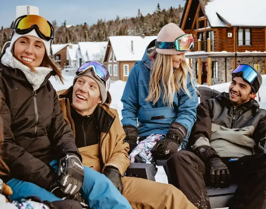 Un groupe de skieurs prenant une pause ensemble tout en portant des vêtements d'hiver et des lunettes de ski.